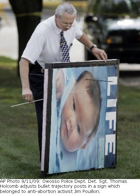 AP Photo: Owosso Police Detective Sargeant Thomas HOlcomb adjusts bullet trajectory posts in a sign which belonged to pro-life activist Jim Pouillon